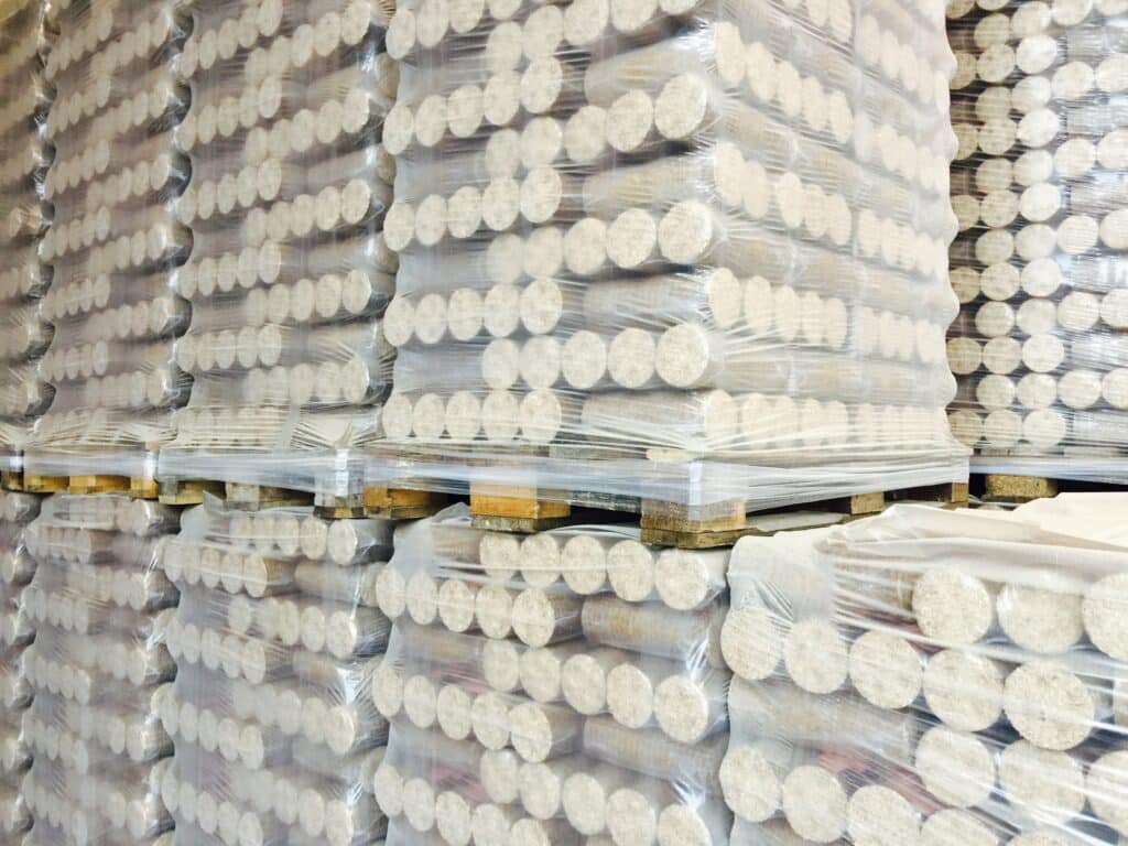 Pallets met ronde briketten in folie in een magazijn